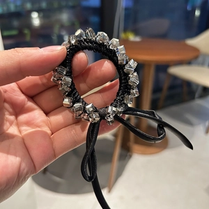 Close-up of faceted crystal cubes and leather bow decoration on the black hair tie