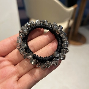 Close-up of square faceted crystal beads on a black elastic hair tie held in hand
