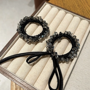 Close-up of black beaded hair ties with cube crystals and elegant ribbon on soft velvet