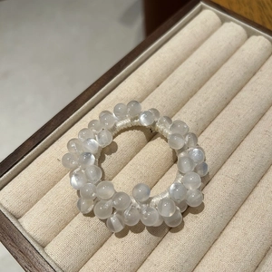 Macro shot of opal bead hair scrunchie with soft moonstone glow on beige display tray