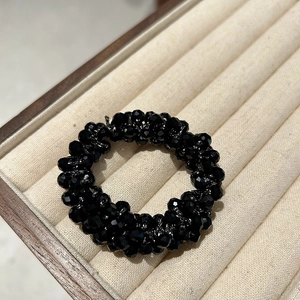 Dettaglio delle perle di cristallo nero sfaccettate sull'elastico per capelli