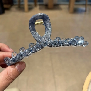 Detail of blue fabric hair claw clip with crystal bead strands and metal frame base