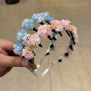 Detailed view of handmade beaded flower headbands in pastel pink, blue, and champagne gold
