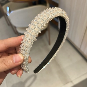Close-up of champagne crystal headband with sparkling rhinestones and black inner base