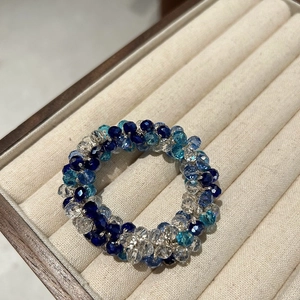 Dettaglio delle perle di cristallo blu e trasparenti su un elastico per capelli raffinato