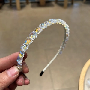 Détail montrant les perles en cristal irisé sur un serre-tête en métal argenté fin