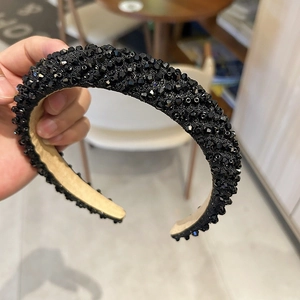 Gros plan détaillé sur un serre-tête noir large orné de cristaux étincelants et doublure beige