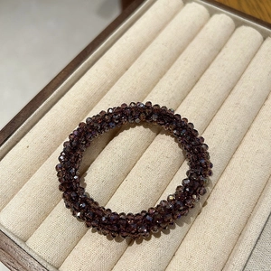 Close-up of a deep purple faceted crystal hair tie displayed in a beige velvet jewelry box