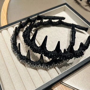 Detail of gothic punk headband featuring black conical spikes and grey crystal beads