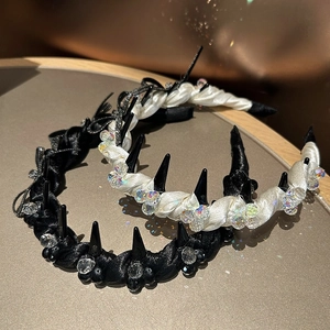 Detail of satin headbands with punk spikes and crystal beads on a beige tray