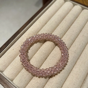 Close-up of pink faceted crystal beads hair tie on a beige velvet jewelry display
