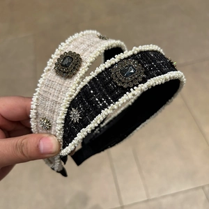 Detailed view of tweed fabric texture with faux pearls and dark square gemstones on headbands