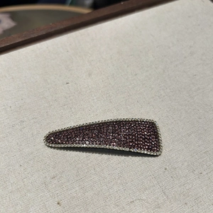Detailed close-up of a luxury triangular hair clip with purple and white rhinestones