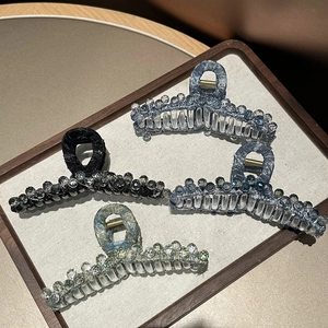 Detail view of large crystal shark hair clips in four elegant shimmering fabric colors