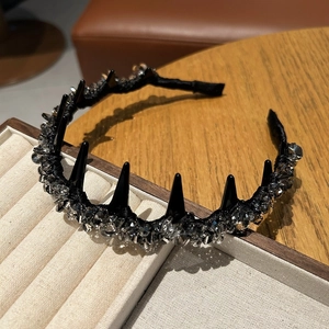 Detail of spiked crystal headband featuring black studs and grey rhinestones on a beige tray