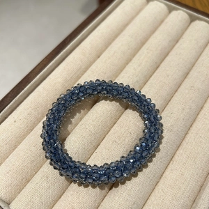 Detail of blue crystal beaded hair tie with faceted beads in a soft cream jewelry tray