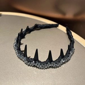 Detail of beaded black headband featuring glossy punk spikes and grey crystal accents