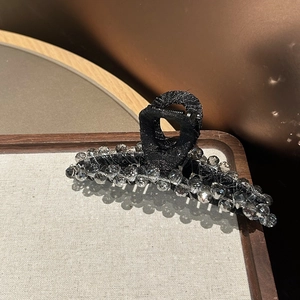 Close-up of elegant black hair claw clip with faceted grey crystals and vintage texture