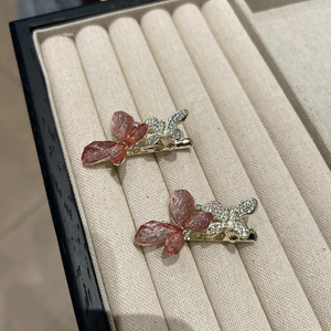 Détail de la pince à cheveux papillon rose avec strass sur boîte à bijoux beige