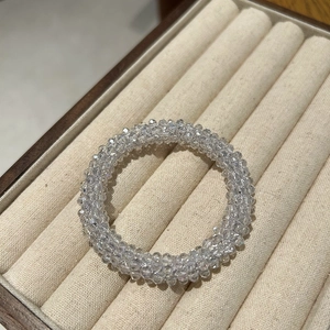Detail of multi-layer crystal bead hair tie with white pearls in a beige jewelry box