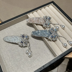 Gros plan de barrettes noeuds scintillantes avec perles et pompons sur présentoir beige