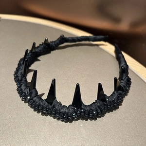 Macro shot of black gothic headband with crystal beads and 3D spikes on satin fabric
