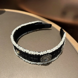 Detailed macro view of black tweed headband with pearl trim and crystal brooch detail