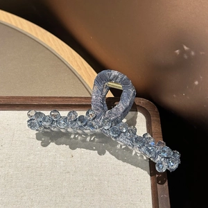 Detail of blue silk fabric shark hair claw clip with light blue crystal beads and gold spring