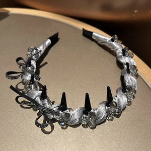 Detailed view of silver satin headband with black bow, crystal beads and punk spikes
