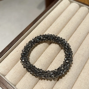 Detail of dark grey faceted crystal beads and elastic hair band in beige velvet box