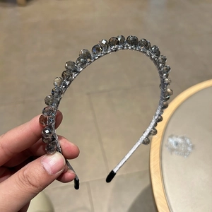 Détails d'un serre-tête artisanal avec perles en cristal gris et tissu argenté poli