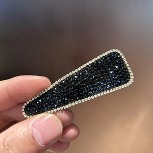 Close-up of luxury rectangular hair clip with black rhinestones and gold metal finish