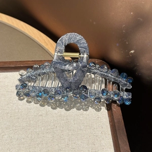 Close-up of elegant hair claw clip with grey-blue fabric and sparkling crystal beads