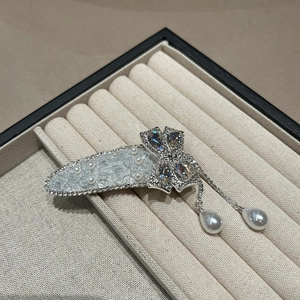 Détail d'une pince à cheveux argentée avec nœud, strass et pampilles de perles