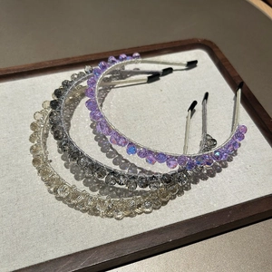Gros plan de serre-têtes perlés de luxe en violet, gris et champagne sur un plateau
