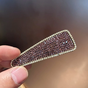 Macro shot of luxury rectangular hair clip with purple rhinestones and gold finish