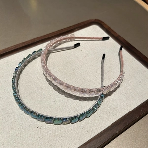 Détail de serre-têtes en cristal scintillant rose et émeraude sur un plateau en lin