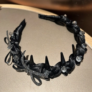 Detailed macro view of black satin headband with punk spikes and rhinestone bow