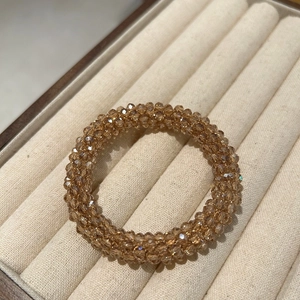 Detailed macro view of champagne beaded crystal hair tie in beige velvet jewelry box