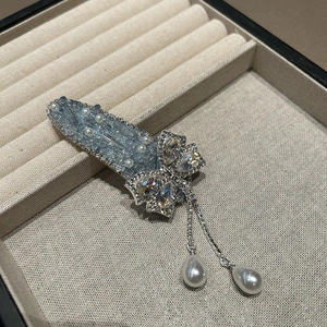 Détail de la pince à cheveux papillon avec cristaux bleus, chaîne argentée et perles