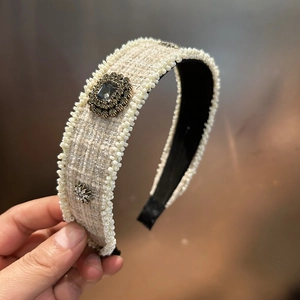 Detail of beige tweed headband with pearl trim and vintage metal floral ornaments