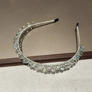 Détail macro du serre-tête de luxe en cristal avec perles brillantes et satin doux