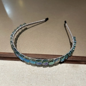 Détail de cristaux carrés chatoyants bleu-vert sur un serre-tête fin fait à la main