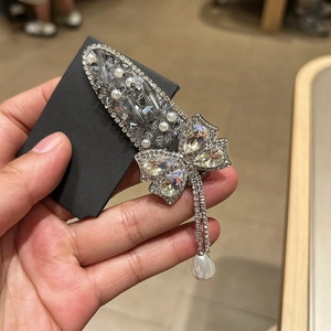 Détail d'une barrette argentée avec strass, perles et pampilles scintillantes