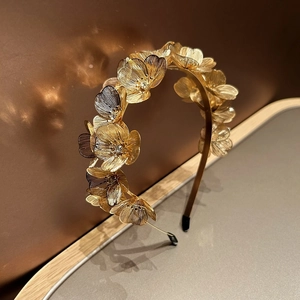 Close-up of golden metal ginkgo flower headband with sparkling rhinestones and woven petals