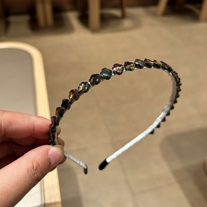 Détail de perles de cristal facettées sur un serre-tête fin aux reflets ambre et gris
