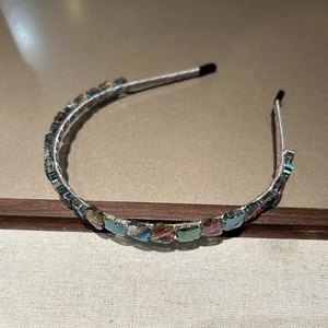 Détail du serre-tête en cristal trèfle irisé avec armature en fil argenté et embouts noirs