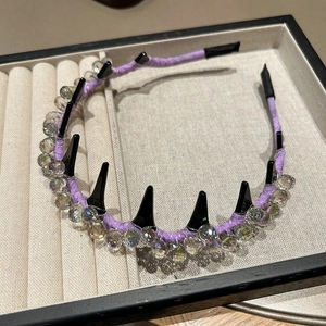 Nahaufnahme des lila Kristall Stirnbandes mit schwarzen Punk Spikes auf Schmucktablett