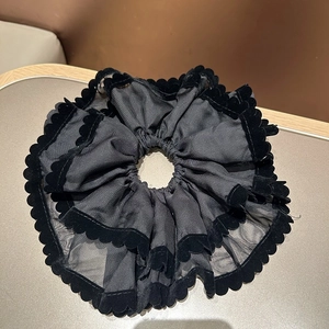 Vue détaillée du chouchou en organza noir double couche avec bords ondulés en velours