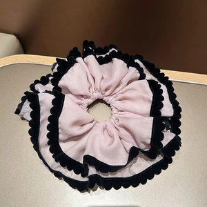 Détail d'un chouchou bouffant en mousseline rose-violet avec bordure en velours noir
